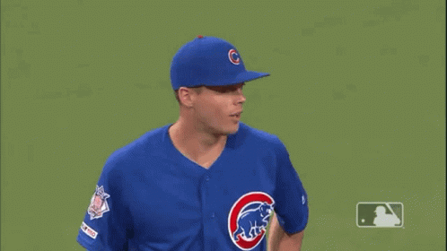 A Baseball Player Wearing A Blue Cubs Uniform Is Standing On A Green Field . GIF