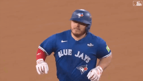 A Baseball Player Wearing A Blue Jays Uniform Is Running On The Field . GIF