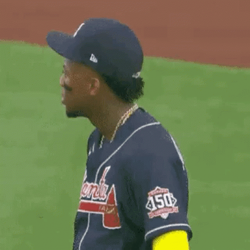 A Baseball Player Wearing A Blue Jersey And A Hat Is Standing On A Field . GIF
