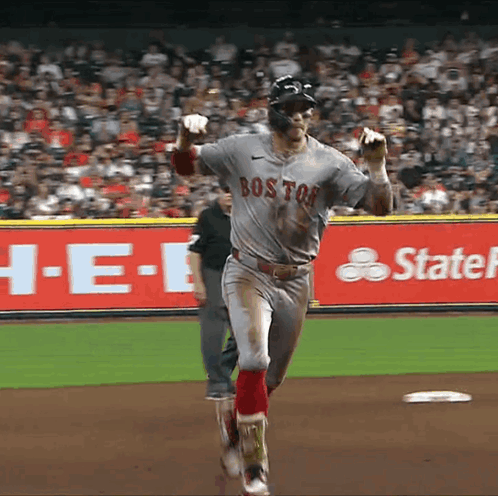 a baseball player wearing a boston jersey is running towards the base