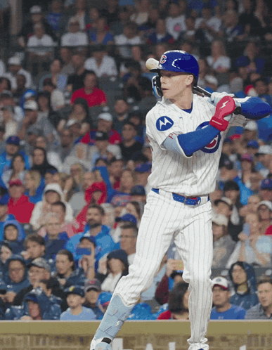 a baseball player wearing a chicago cubs uniform swings his bat
