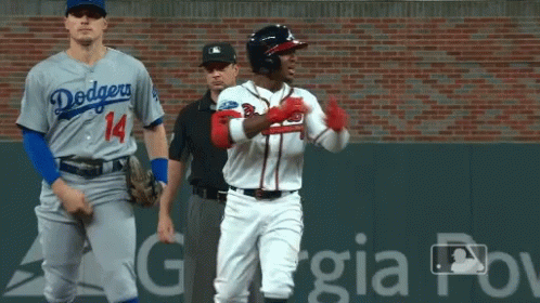 A Baseball Player Wearing A Dodgers Jersey Stands Next To An Atlanta Braves Player GIF