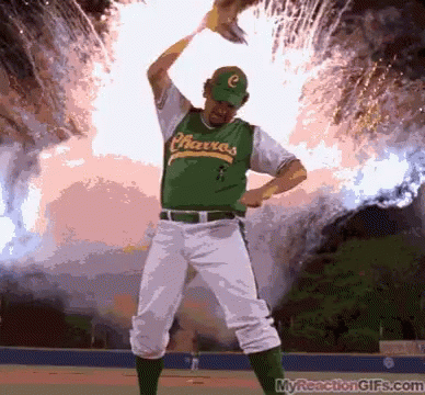 A Baseball Player Wearing A Green Charcos Jersey Stands In Front Of A Fireworks Display GIF
