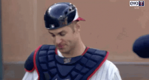 A Baseball Player Wearing A Helmet And A Chest Protector Is Standing On A Field . GIF