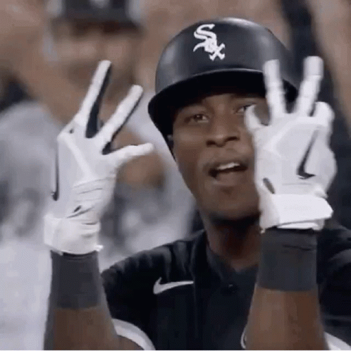 A Baseball Player Wearing A Helmet And Gloves Is Giving The Peace Sign . GIF