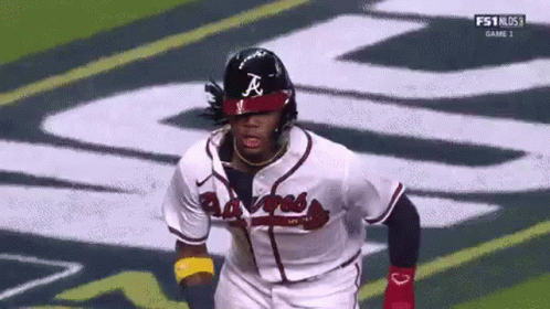 A Baseball Player Wearing A Helmet Is Running On The Field During A Game . GIF