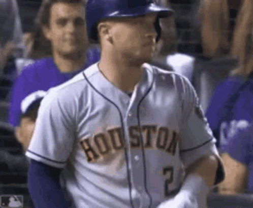 A Baseball Player Wearing A Houston Jersey And A Helmet Is Standing In The Dugout . GIF
