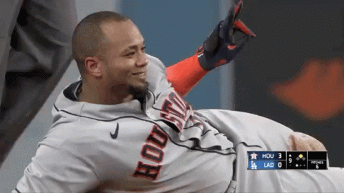 A Baseball Player Wearing A Houston Jersey Is Laying On The Ground . GIF