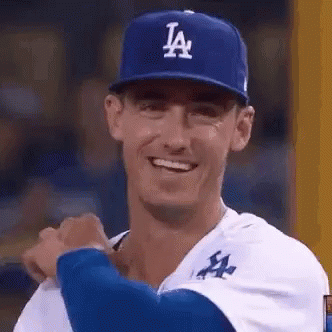A Baseball Player Wearing A La Hat Is Smiling While Standing On The Field . GIF