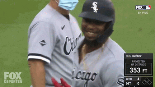 a baseball player wearing a mask is being hugged by another player