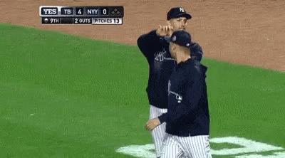 A Baseball Player Wearing A New York Yankees Hat Is Smoking A Cigarette In Front Of A Crowd . GIF