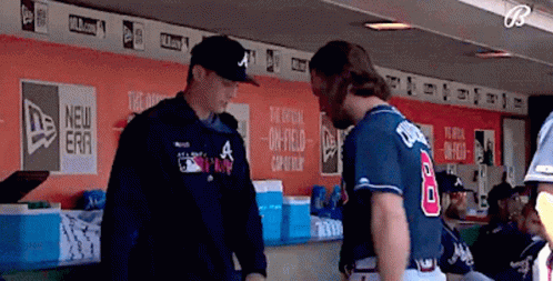 A Baseball Player Wearing A Number 8 Jersey Talks To Another Player In A Dugout GIF
