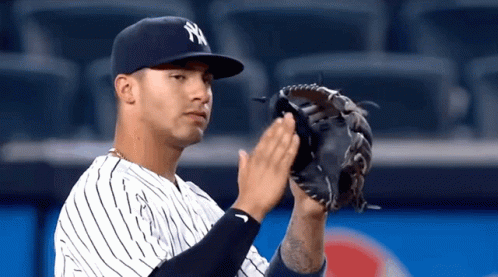 A Baseball Player Wearing A Ny Hat And Glove Is Clapping His Hands GIF
