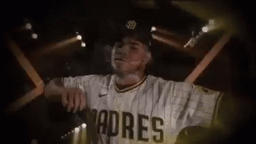 A Baseball Player Wearing A Padres Jersey And Hat Is Standing In Front Of A Stage . GIF