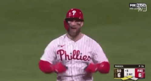 A Baseball Player Wearing A Phillies Jersey Is Standing On A Baseball Field With His Arms In The Air . GIF