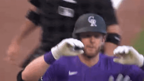 A Baseball Player Wearing A Purple Jersey And A Black Helmet Is Being Hugged By His Teammates . GIF