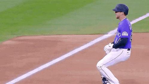 A Baseball Player Wearing A Purple Jersey With The Number 24 On It Is Running Towards The Base . GIF