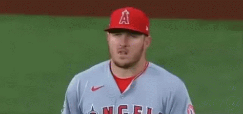 A Baseball Player Wearing A Red Hat And A Grey Jersey Is Standing On The Field . GIF