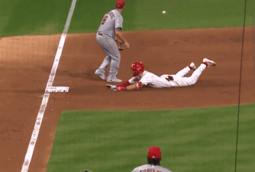 A Baseball Player Wearing A Red Helmet Is Running Towards Home Plate GIF