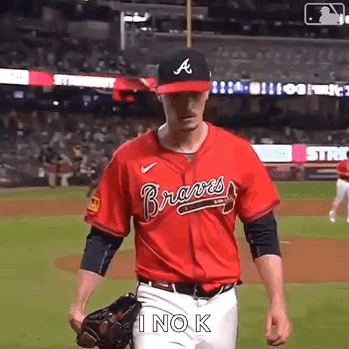 A Baseball Player Wearing A Red Jersey And A Black Hat Is Walking On The Field . GIF