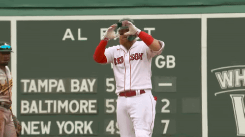 A Baseball Player Wearing A Red Sox Jersey Is Standing In Front Of A Scoreboard GIF