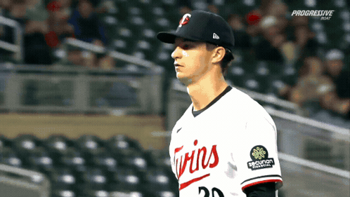 A Baseball Player Wearing A Twins Uniform Stands In The Outfield GIF