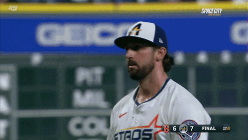 A Baseball Player Wearing A White Astros Jersey Stands In Front Of A Scoreboard GIF