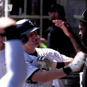 A Baseball Player Wearing A White Sox Helmet Is Being High Fived By His Teammates GIF
