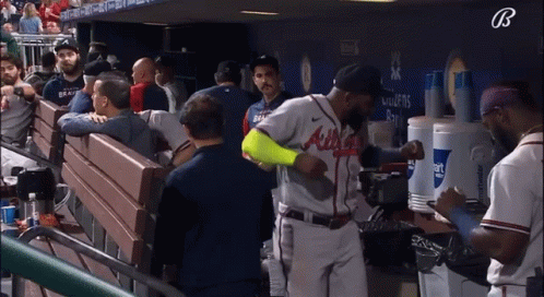 A Baseball Player Wearing An Atlanta Braves Jersey Stands In A Dugout GIF