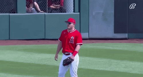 A Baseball Player Wearing Sunglasses And A Red Uniform Is Standing On The Field . GIF