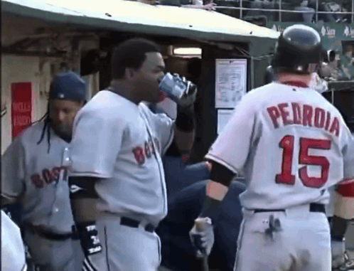 a baseball player with the number 15 on his back drinks from a bottle