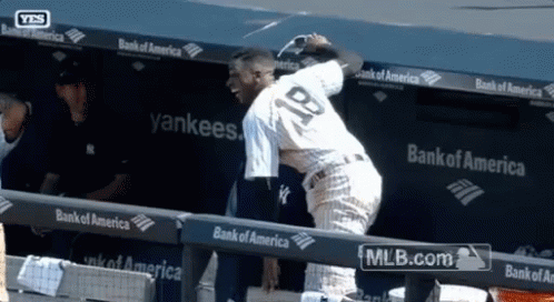A Baseball Player With The Number 18 On His Back Stands In A Dugout GIF