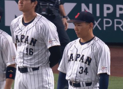 A Baseball Player With The Number 34 On His Jersey Stands Next To Another Player GIF