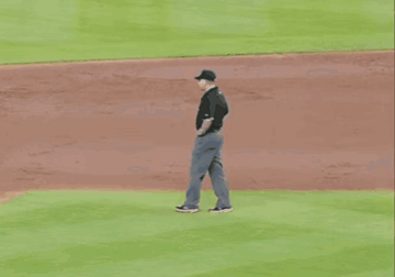 A Baseball Umpire Wearing A Ny Hat Stands On The Mound GIF