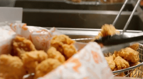 A Basket Of Fried Chicken Is Being Scooped Out Of The Fryer GIF