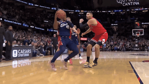 A Basketball Game Being Played In Front Of A Caesars Sportsbook Banner GIF