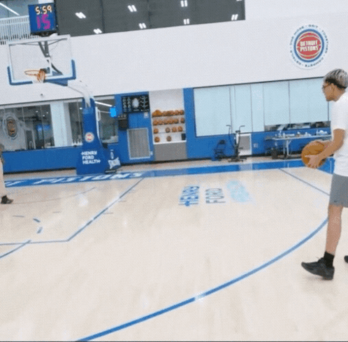 a basketball game is being played in a gym with a scoreboard above the basketball hoop that says 5-5
