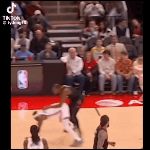 A Basketball Game Is Being Played In Front Of A Crowd And A Referee . GIF