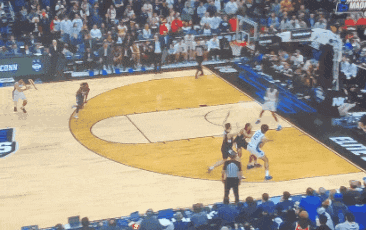 A Basketball Game Is Being Played In Front Of A Crowd With A Banner That Says Conn On It GIF
