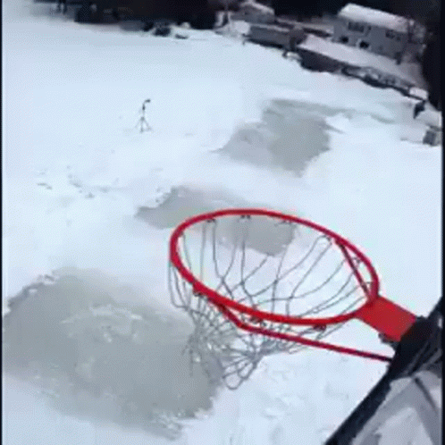 a basketball hoop is sitting in the middle of a snow covered field