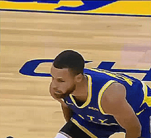 A Basketball Player In A Blue And Yellow Uniform Is Kneeling On The Court . GIF