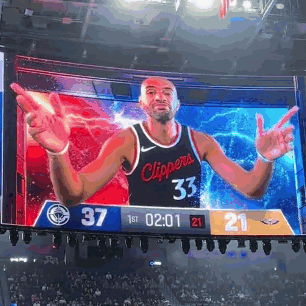A Basketball Player In A Clippers Jersey Is On A Large Screen GIF