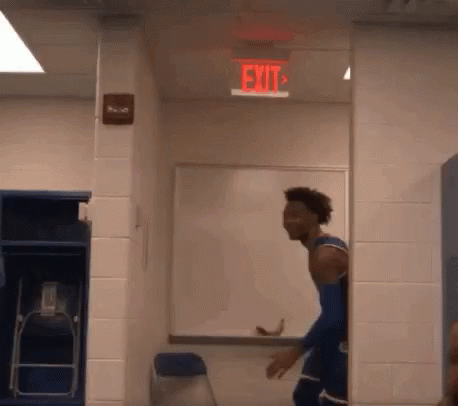 A Basketball Player In A Locker Room With A Red Exit Sign On The Ceiling . GIF