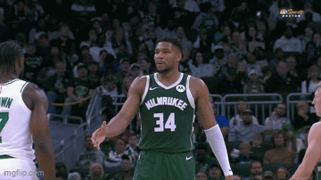 A Basketball Player In A Milwaukee Jersey Is Shaking Hands With Another Player . GIF