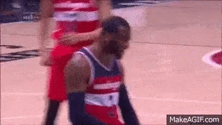 A Basketball Player In A Red White And Blue Jersey Is Kneeling Down On The Court GIF