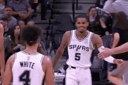 A Basketball Player In A Spurs Jersey Is Shaking Hands With Another Player . GIF