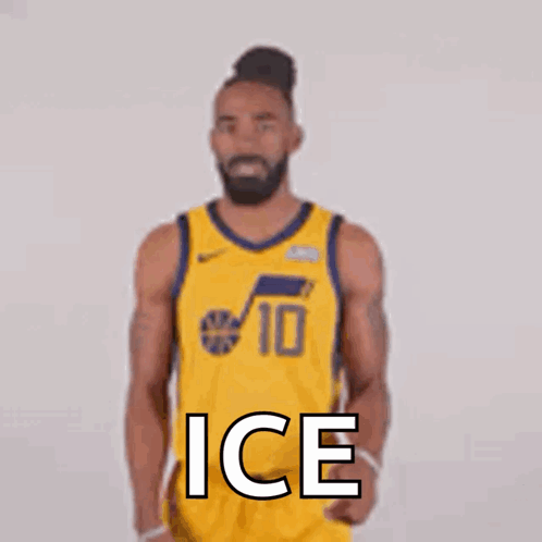 A Basketball Player In A Yellow Jersey Is Standing In Front Of A White Wall . GIF
