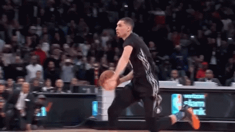 A Basketball Player Is Dribbling A Ball On A Court In Front Of A Verizon Sign . GIF