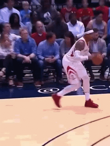A Basketball Player Is Dribbling A Basketball On A Court With A Crowd Watching . GIF