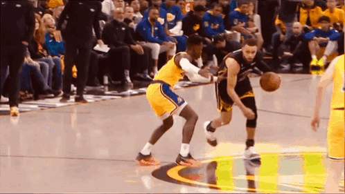 A Basketball Player Is Dribbling A Basketball While Another Player Tries To Stop Him . GIF